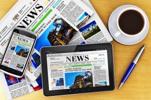 Smartphone and traditional newspaper side by side.